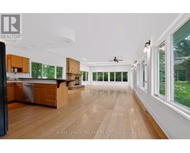 A spacious kitchen with wooden floors and a ceiling fan.
