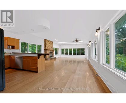 A spacious kitchen with wooden floors and a ceiling fan.