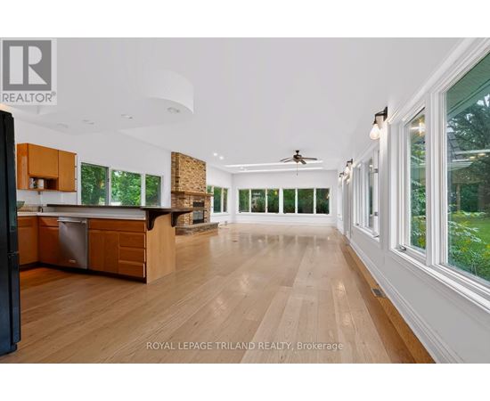 A spacious kitchen with wooden floors and a ceiling fan.