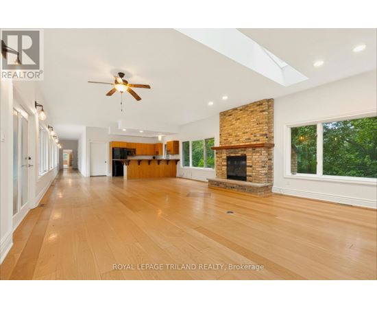 A spacious room with wooden floors and a fireplace.