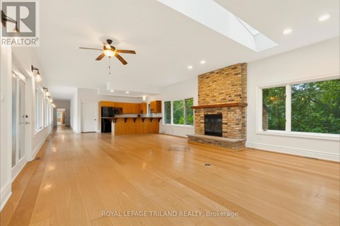 A spacious room with wooden floors and a fireplace.