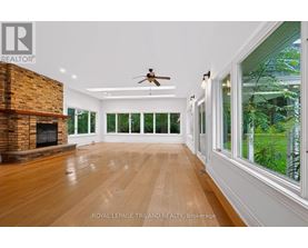 A spacious room with wooden floors and a brick fireplace.