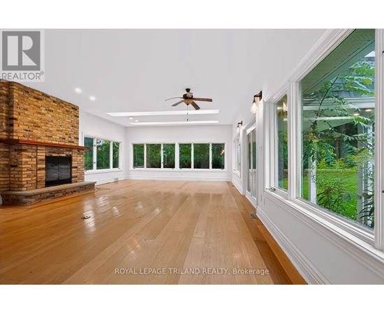 A spacious room with wooden floors and a brick fireplace.