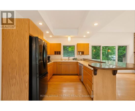 A modern kitchen with wooden cabinets and a black refrigerator.