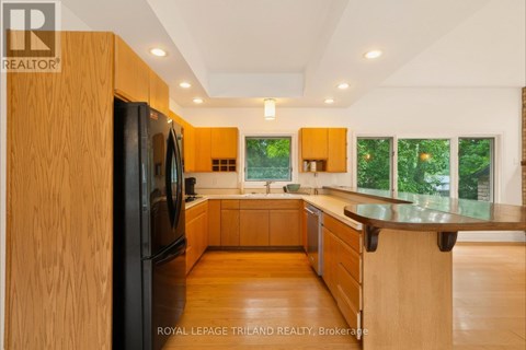 A modern kitchen with wooden cabinets and a black refrigerator.