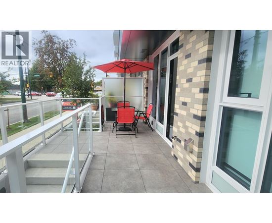 A balcony with a table and chairs and an umbrella.