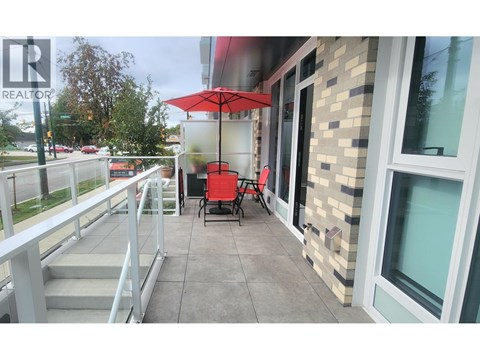A balcony with a table and chairs and an umbrella.