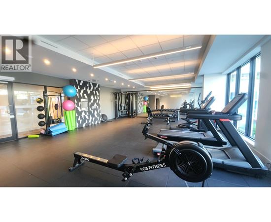 A gym with a variety of equipment including treadmills, exercise bikes, and weights.