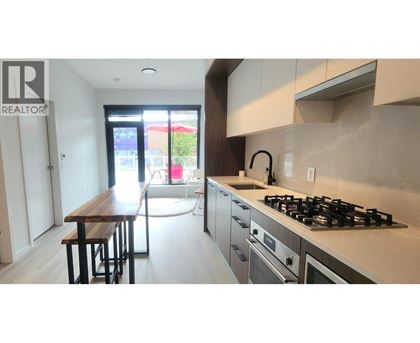 A modern kitchen with a wooden table and stainless steel appliances.