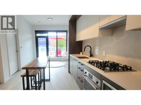 A modern kitchen with a wooden table and stainless steel appliances.