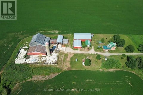 An aerial view of a farm with a red barn and a green field.
