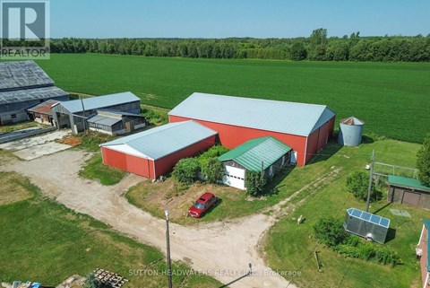 A red barn with a green roof is surrounded by a grassy field.
