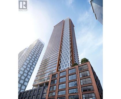 A tall building with a glass facade stands in front of two other buildings.