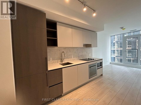 A modern kitchen with white and brown cabinets and a large window.