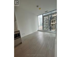 A spacious room with wooden flooring and a large window overlooking a cityscape.