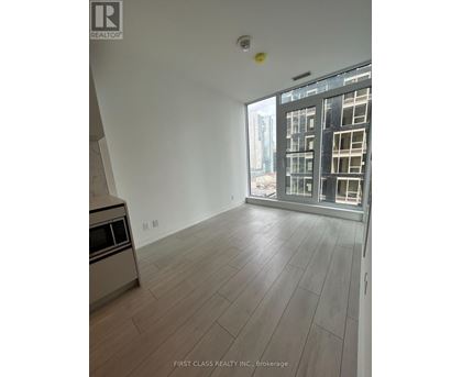 A spacious room with wooden flooring and a large window overlooking a cityscape.