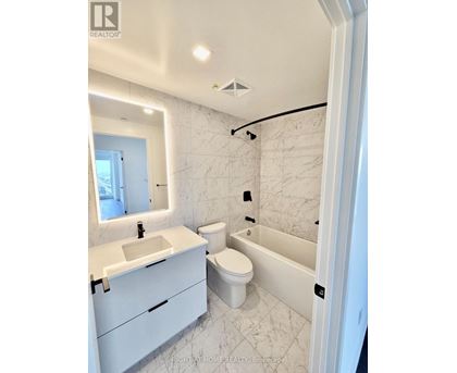 A white bathroom with a marble tile wall and a white toilet.