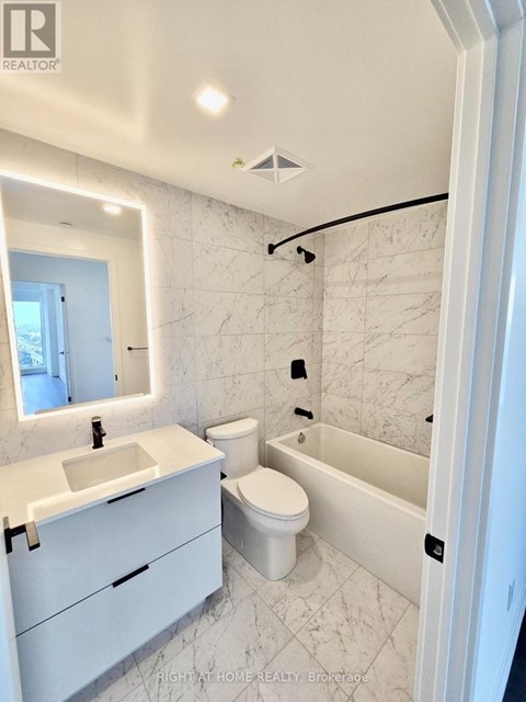 A white bathroom with a marble tile wall and a white toilet.