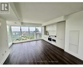 A spacious room with wooden floors and a large window overlooking a cityscape.