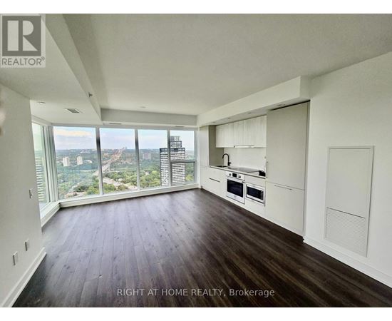 A spacious room with wooden floors and a large window overlooking a cityscape.