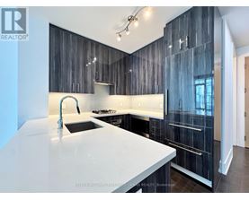 A modern kitchen with a white countertop and dark wood cabinets.