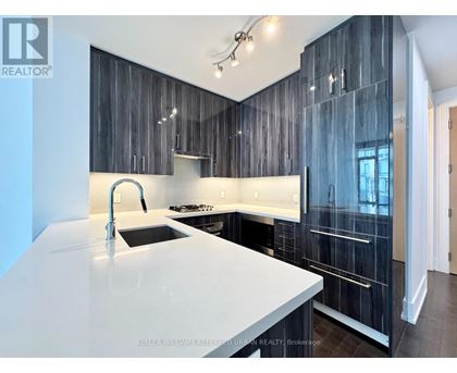 A modern kitchen with a white countertop and dark wood cabinets.