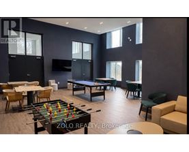A foosball table is in the middle of a room with a pool table and a couch.