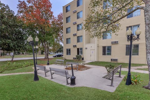 A large beige building with a tree in front of it.