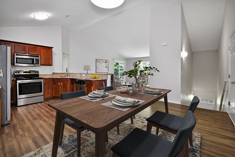 A modern kitchen with a wooden table set for two.