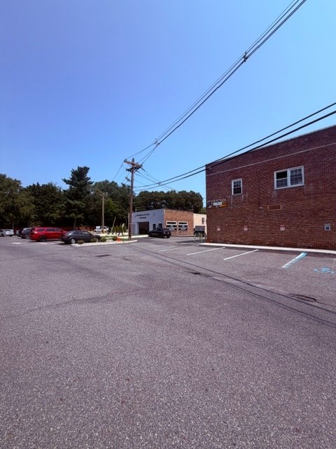A parking lot with a red car and a brick building.