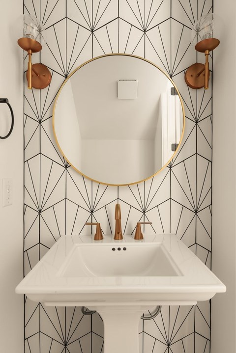 A bathroom sink with a round mirror above it.