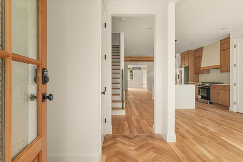 A hallway with a wooden floor and a white door.