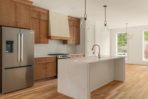 A modern kitchen with wooden cabinets and a marble island.