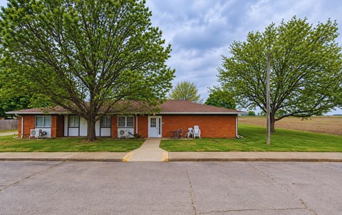 A red brick house with a tree in front.