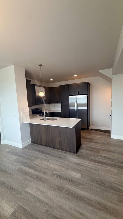 A modern kitchen with a wooden island and dark cabinets.