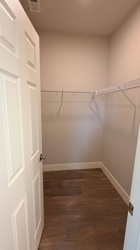 A white door is open to a room with a wooden floor and a white wall.