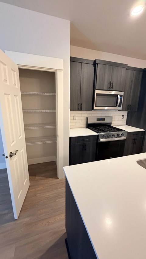A kitchen with a white counter top and black cabinets.