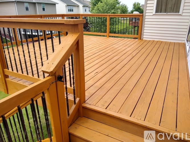 A wooden deck with a railing and steps leading to a house.