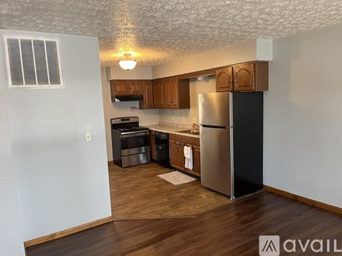 A kitchen with wooden cabinets and a black fridge.