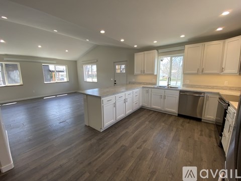 A spacious kitchen with white cabinets and a wooden floor.