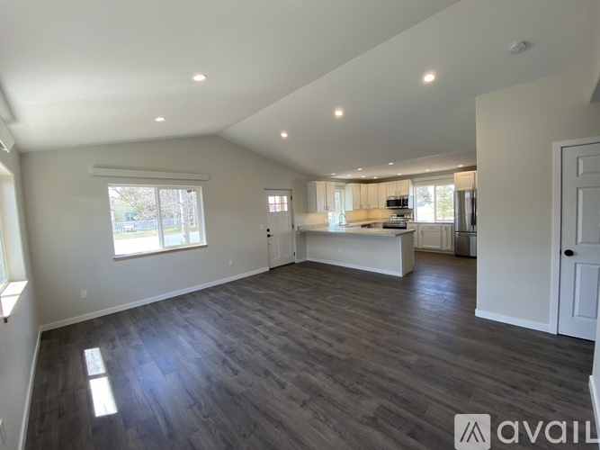 A spacious room with wooden flooring and white walls.