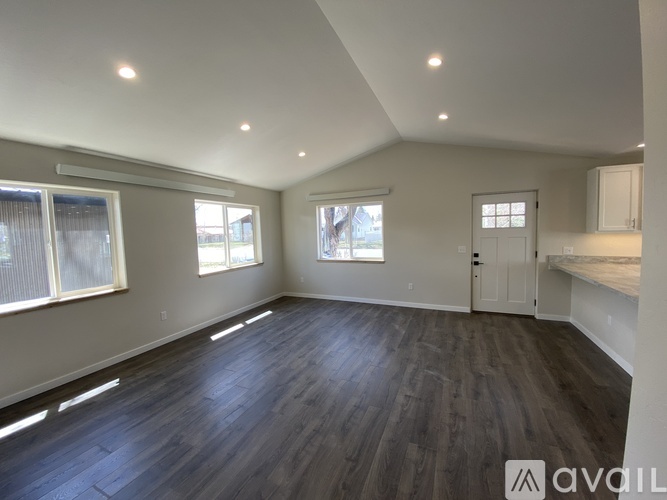 A spacious room with wooden flooring and white walls.