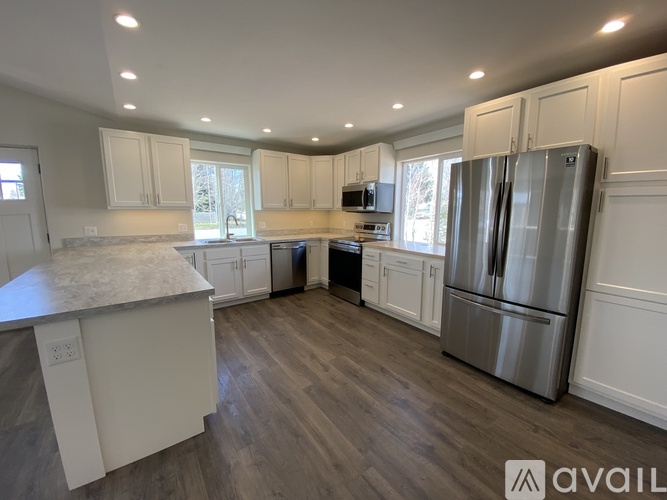 A kitchen with white cabinets and a stainless steel refrigerator.