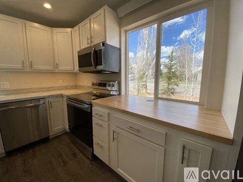 A kitchen with white cabinets and a window overlooking a snowy landscape.