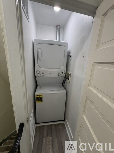 A small white portable toilet is in a narrow hallway.
