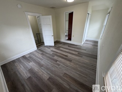 A room with wooden flooring and white walls.