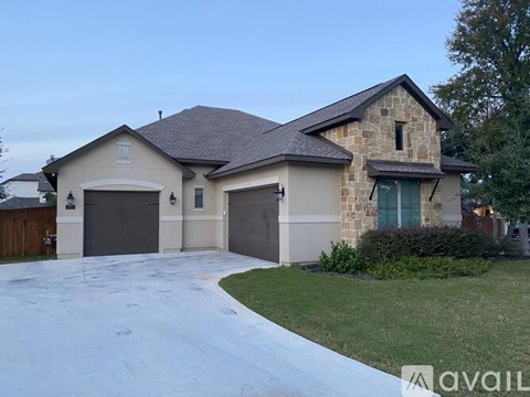 A house with a stone facade and a large driveway.