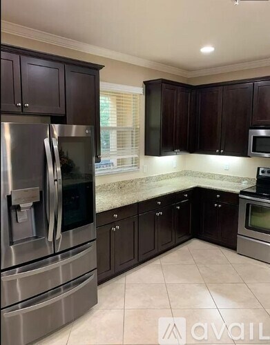 A kitchen with dark brown cabinets and stainless steel appliances.