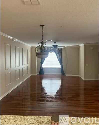 A long hallway with wood floors and a chandelier.
