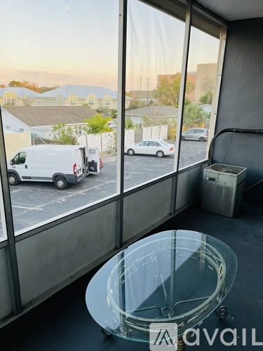 A glass table is in front of a window with a view of a parking lot.